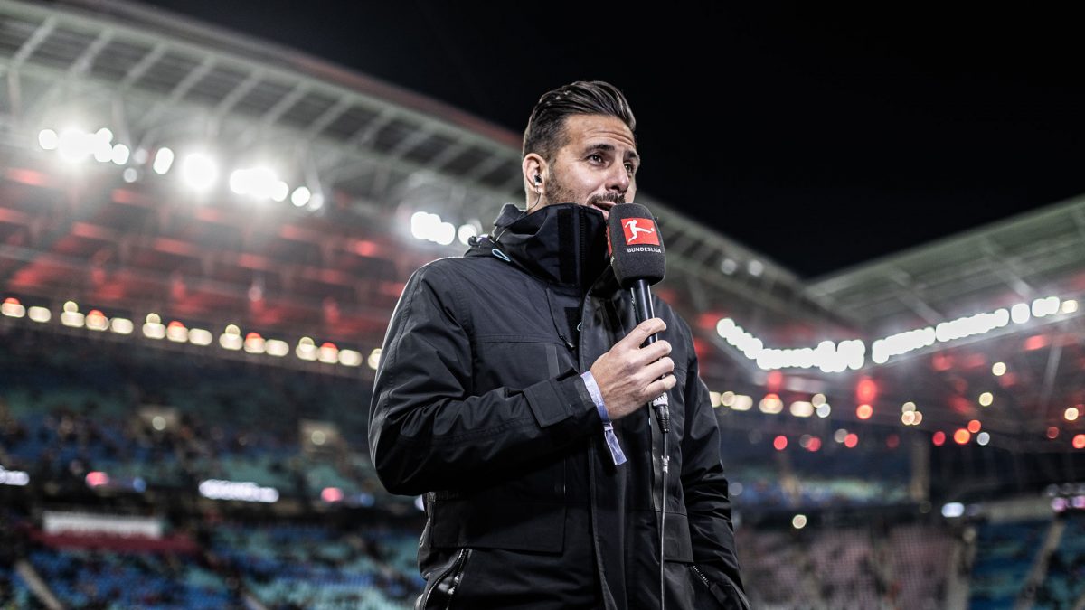 Claudio Pizarro standing with a microphone on the pitch of the Red Bull Arena in Leipzig.